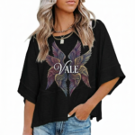: A person wearing an oversized breathable cotton shirt featuring a "VALE" logo with colorful layered angel wings on the front, available in green, black, and purple.