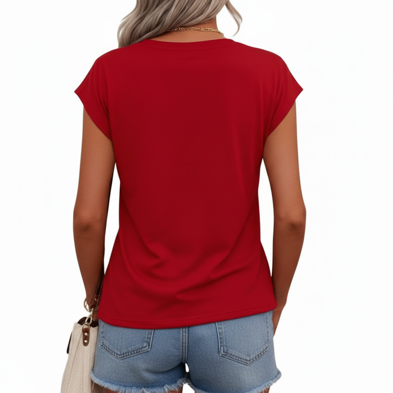 Professional studio shot of a woman wearing a VALE brand V-neck breathable cotton t-shirt with a metallic gold cursive logo, styled with denim jeans and gold accessories.