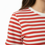 Woman wearing a breathable red and white striped cotton t-shirt with VALE embroidery and blue jeans, isolated on a white background. / Woman wearing an orange and white striped cotton crew neck t-shirt with VALE chest embroidery.