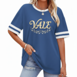 Woman wearing VALE graphic cotton t-shirt with striped sleeves and laurel wreath design in Blue, Plum, and Cream colors.