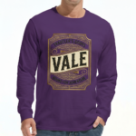 A man wearing a VALE Traveler’s Goods long-sleeve cotton shirt featuring a vintage-style gold and cream graphic label that says "Bound for Adventure" on the chest.