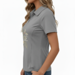 Female model wearing a slim-fit breathable cotton pique polo shirt featuring a "VALE" botanical graphic with ferns, flowers, and a dragonfly. Available in Forest Green, Charcoal Grey, and Earthy Brown.
