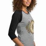 Woman wearing a breathable cotton raglan 3/4 sleeve shirt featuring a vintage nautical compass "VALE" graphic design, available in Grey/Black, White/Grey, and Olive/Black colorways.
