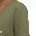 A woman wearing a breathable cotton V-neck t-shirt with a floral "Vale" graphic design, available in orange, khaki, and olive green colors.