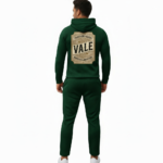 Man wearing a textured breathable cotton tracksuit with a vintage traveler's badge on the back, available in Obsidian Navy, Forest Green, and Heather Charcoal.