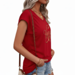 Professional studio shot of a woman wearing a VALE brand V-neck breathable cotton t-shirt with a metallic gold cursive logo, styled with denim jeans and gold accessories.