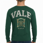 Back view of a man wearing a VALE graphic long-sleeve cotton shirt featuring a vintage gate design and Roman numerals MCMXCIX.