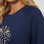 Woman wearing a breathable cotton 3/4 sleeve raglan shirt featuring a gold-toned floral "VALE" crest design, available in Navy Blue, Earthy Brown, and Maroon.
