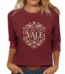 Woman wearing a breathable cotton 3/4 sleeve raglan shirt featuring a gold-toned floral "VALE" crest design, available in Navy Blue, Earthy Brown, and Maroon.