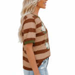 A woman wearing a breathable cotton striped t-shirt featuring a white rose wreath graphic and contrast green neckline, paired with blue denim.