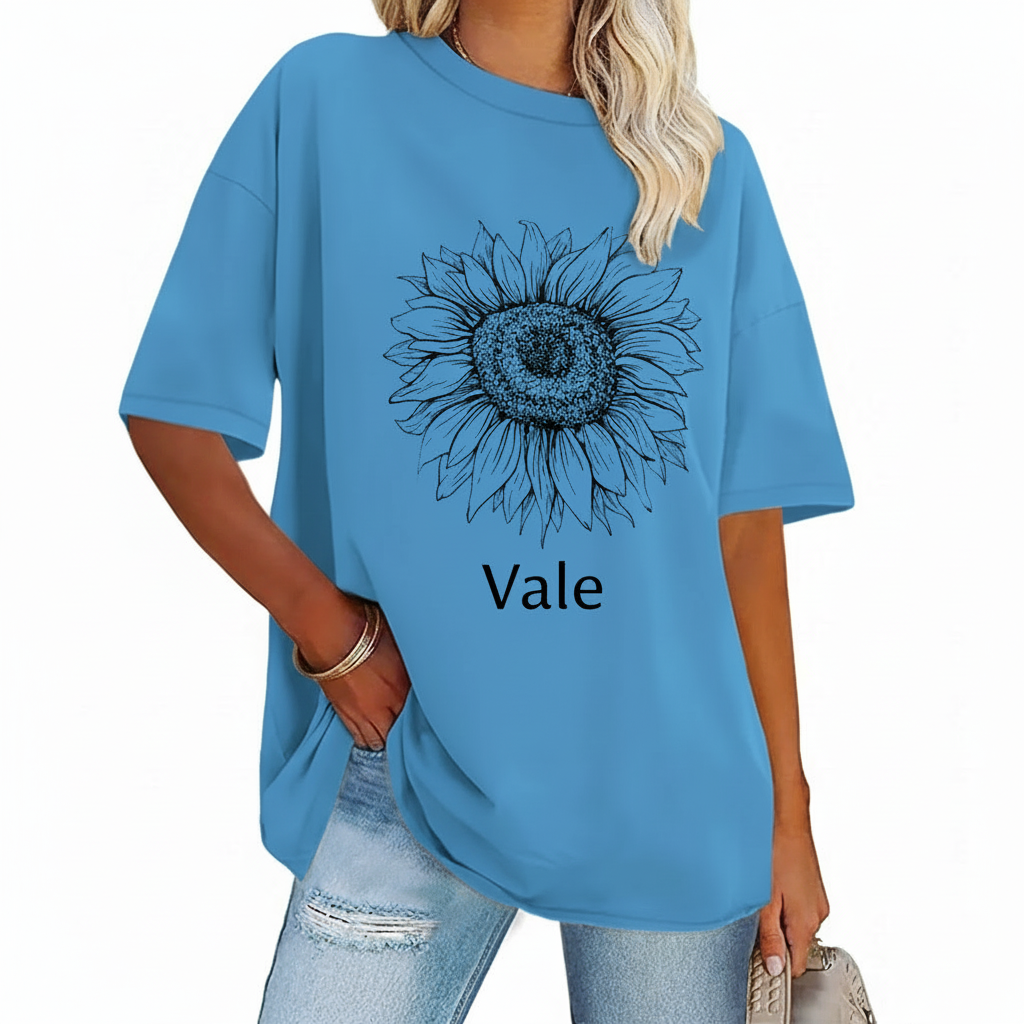 Oversized Sunflower Graphic T-Shirt Front view of a woman wearing a Vale brand oversized cotton t-shirt featuring a large black line-art sunflower graphic, available in beige, blue, and green.