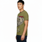 Front view of a man wearing a VALE brand steampunk graphic t-shirt featuring internal watch gears and cogs design, 100% cotton breathable fabric, available in Olive, Grey, and White.