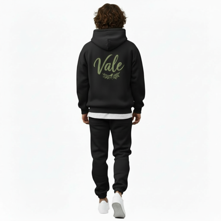 A man wearing a premium breathable cotton tracksuit featuring a sage green "Vale" script logo and olive branch graphic on the back, available in Black, Charcoal Grey, and Burgundy.