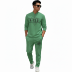 A professional male model wearing a VALE minimalist cotton tracksuit featuring a quarter-zip sweatshirt and matching joggers, isolated on a white background.