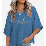 Woman wearing a breathable cotton oversized "Vale" t-shirt with gold script lettering and horizontal seam detail, available in green, blue, and red.