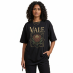 A woman modeling an oversized VALE brand t-shirt featuring a vintage-style Protea flower graphic and celestial symbols. Available in black, grey, and cream colors.