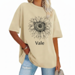 Front view of a woman wearing a Vale brand oversized cotton t-shirt featuring a large black line-art sunflower graphic, available in beige, blue, and green.
