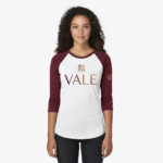 Woman wearing a VALE branded 3/4 sleeve raglan cotton shirt with metallic copper logo, athletic slim fit baseball style.