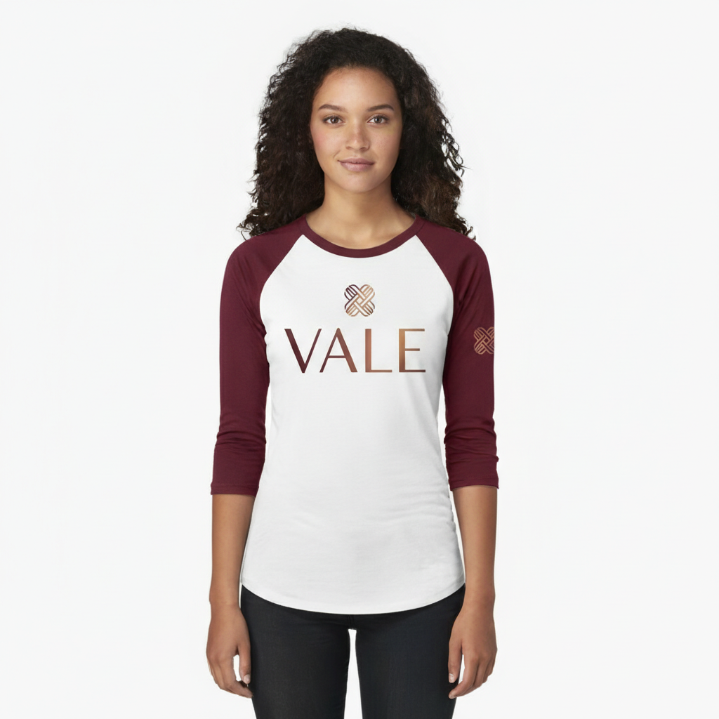 Woman wearing a VALE branded 3/4 sleeve raglan cotton shirt with metallic copper logo, athletic slim fit baseball style.
