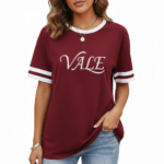 Woman wearing VALE graphic print ringer t-shirt in maroon, grey, and beige colors with varsity sleeve stripes.