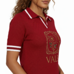 A high-quality studio shot of a model wearing a VALE brand breathable cotton polo shirt featuring white-tipped collars and a detailed gold floral celestial embroidery on the chest.
