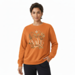 Person wearing a VALE graphic cotton sweatshirt featuring botanical leaves, acorns, and stars in Black, Forest Green, and Burnt Orange colors.