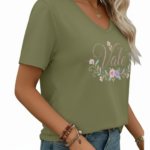 A woman wearing a breathable cotton V-neck t-shirt with a floral "Vale" graphic design, available in orange, khaki, and olive green colors.
