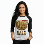 Woman wearing a VALE brand raglan shirt featuring a detailed gold mechanical watch gear graphic and steampunk-style typography on breathable cotton fabric.