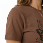 Woman wearing a Vale brand butterfly graphic t-shirt in brown, white, and maroon, featuring a vintage botanical butterfly design on 100% breathable cotton fabric.