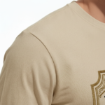 A man wearing a VALE Traveler’s Goods long-sleeve cotton shirt featuring a vintage-style gold and cream graphic label that says "Bound for Adventure" on the chest.