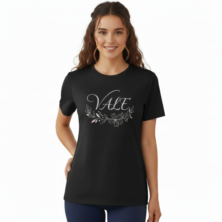 A female model showcasing the VALE branded floral graphic t-shirt in Navy Blue, Black, and White. 100% breathable cotton fabric featuring a silver script logo and elegant floral wreath design on a clean white background.