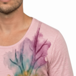 A man wearing a long-sleeved cotton shirt featuring a vertical watercolor tree design with the word "VALE" hidden in the trunk and branches.