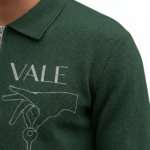 Front view of a professional male model wearing a VALE brand textured cotton tracksuit featuring a quarter-zip polo sweatshirt and matching joggers with minimalist graphic logos on the chest and thigh.