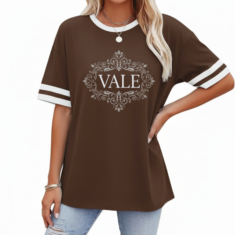 A person wearing a breathable cotton VALE graphic t-shirt with varsity stripes on sleeves, available in black, brown, and orange.
