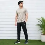 Men wearing beige t-shirt with black track pants sportswear outfit standing outdoors