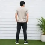 Men wearing beige t-shirt with black track pants sportswear outfit standing outdoors